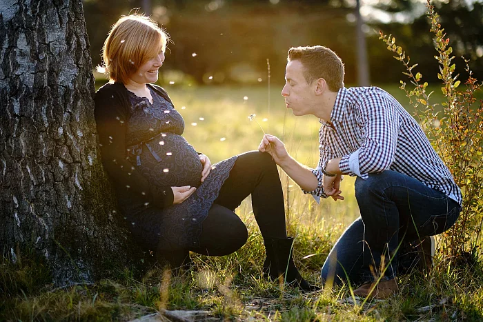 Babybauchshooting Papa pustet ein Blume Richtung werdende Mama